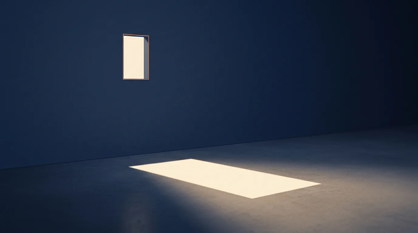 A single small aperture high in a large wall casting one sharply bounded rectangle of light onto a floor that continues far beyond it into shadow