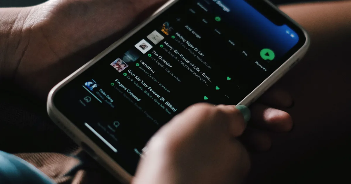 A person using a music-streaming subscription app on their phone, illustrating click-to-cancel and auto-renewal compliance