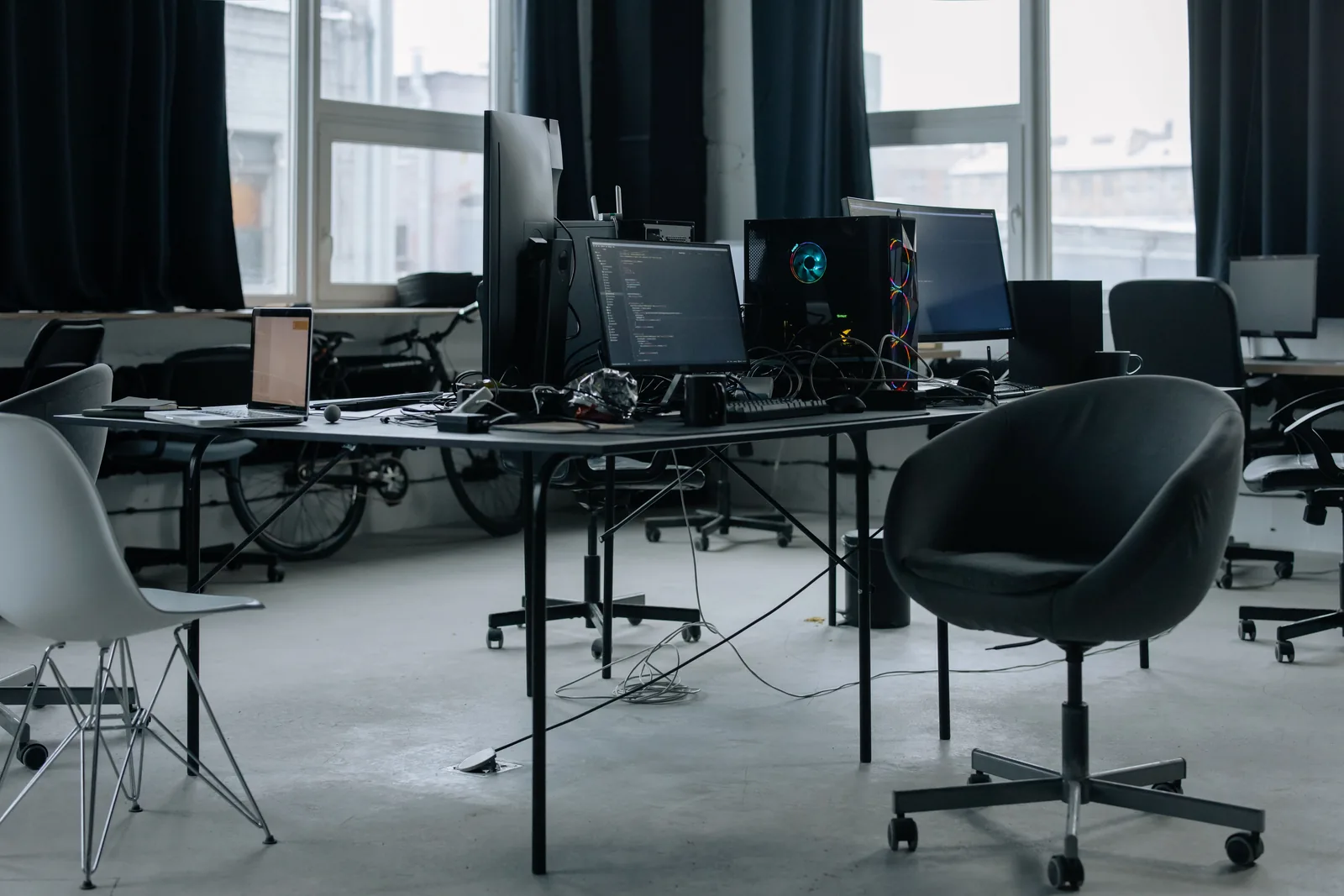 A Silicon Valley startup workspace with monitors showing code, laptops, and developer gear